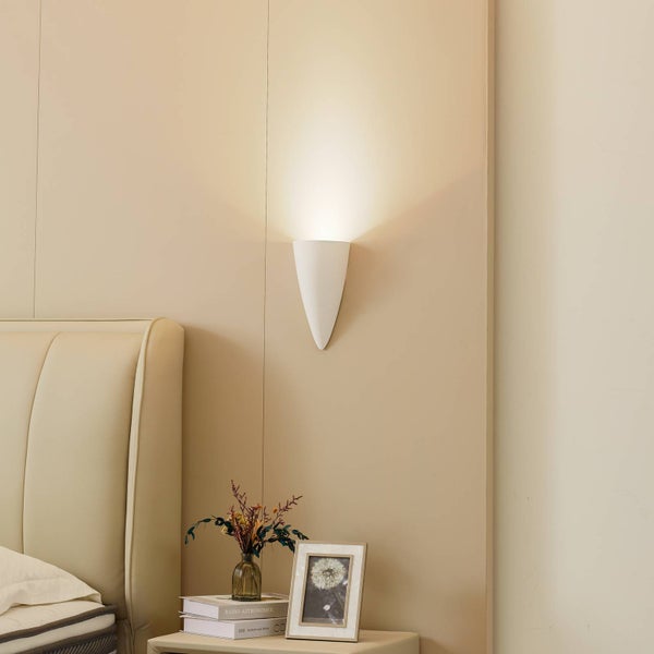 Szene eines Schlafzimmers mit einer weißen Wandleuchte über einem Nachttisch