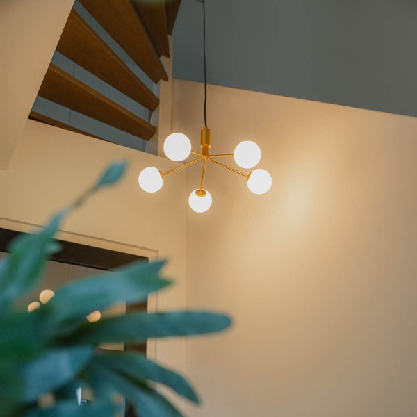 Moderne Deckenleuchte mit fünf Glühbirnen und goldenem Gestell im Innenraum.