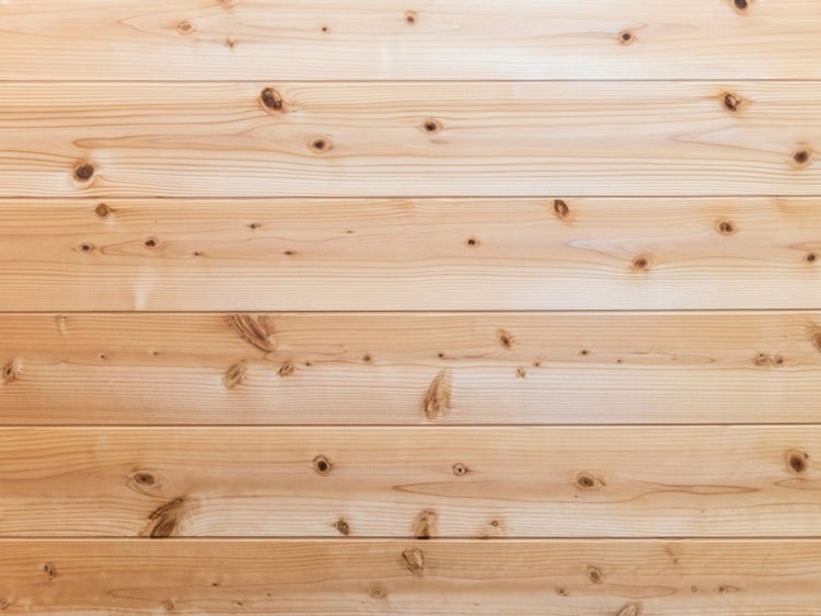 Waagerecht angeordnete Holzpaneele aus Nadelholz mit sichtbaren Astlöchern und Maserung.