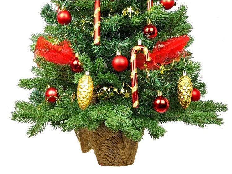 Künstlicher Weihnachtsbaum im Jutesack geschmückt mit Kugeln Zapfen und Zuckerstangen als weihnachtliche Tischdekoration
