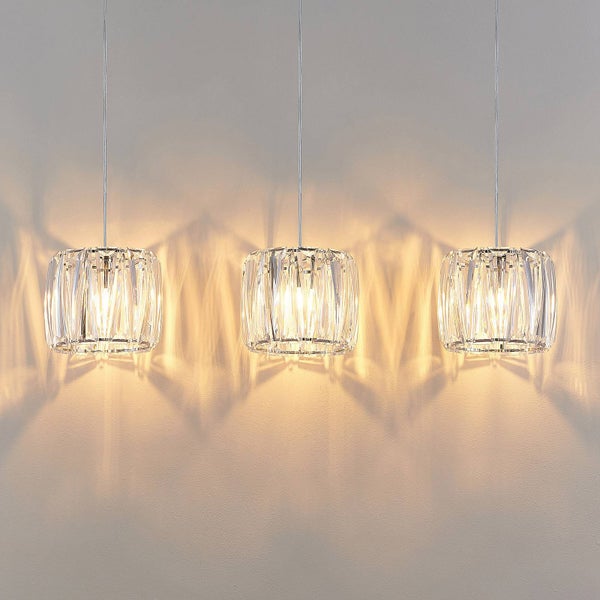 Drei Pendelleuchten mit Kristallglas-Schirmen in einer Reihe, die warmes Licht und Lichtmuster an der Wand erzeugen.