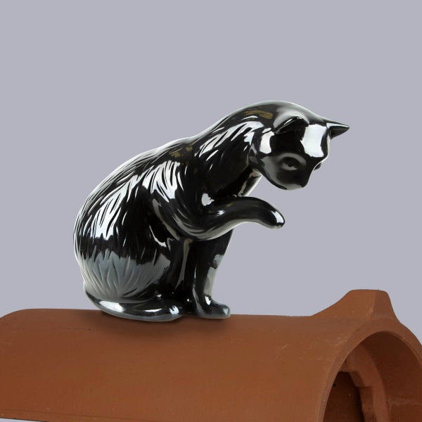 Firstfigur Katze aus Keramik, glänzend schwarz, sitzend auf einem braunen Firstziegel.
