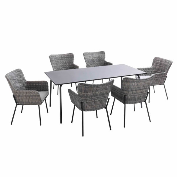 Garten-Essgruppe mit Tisch, sechs Rattanstühlen und Sonnenschirm auf einer Steinterrasse vor einer Backsteinwand.