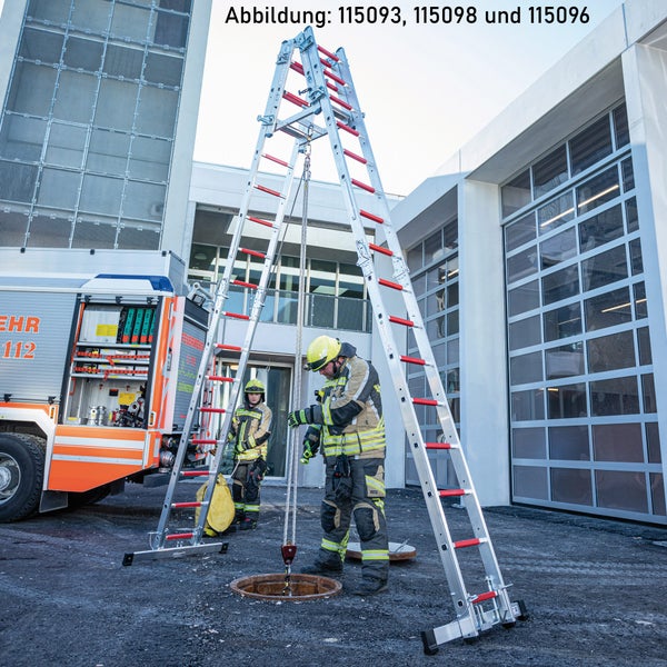 Zwei Feuerwehrleute bereiten eine Rettungsaktion mit einer Drehleiter und einem Abseilsystem vor einem Gebäude vor.