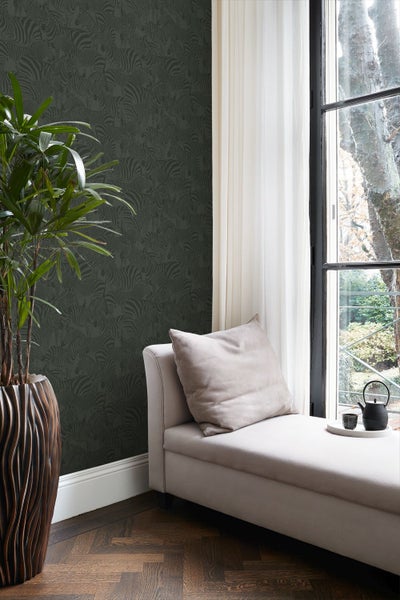 Vliestapete mit Zebramuster in einem hellen Zimmer neben einer Chaiselongue und einer Zimmerpflanze vor einem Fenster.