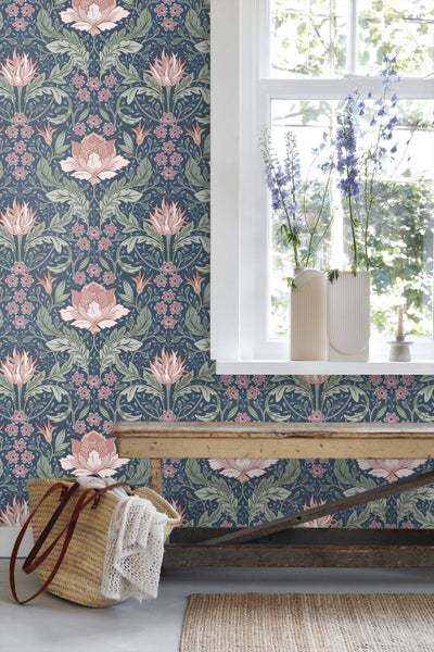Wand mit floraler Mustertapete im Arts and Crafts Stil in einem hellen Raum mit Holzbank und Fenster.