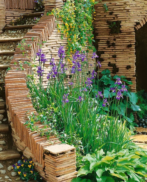 Gartenszene mit Ziegelmauer, Treppe und blühenden Pflanzen