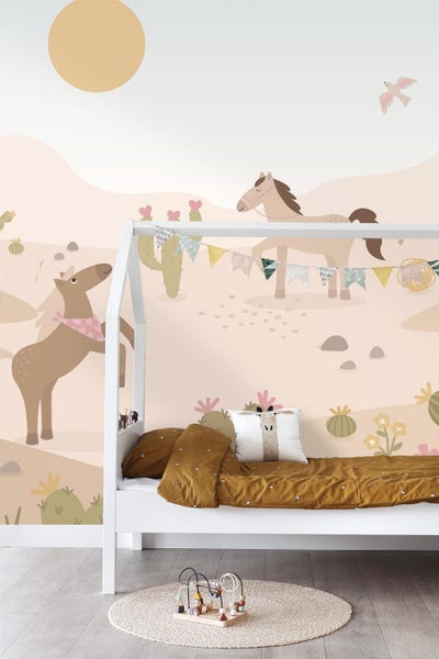 Kinderzimmer mit Pferdefototapete, weißem Hausbett, ockerfarbener Bettwäsche und Kakteen in einer Wüstenlandschaft.