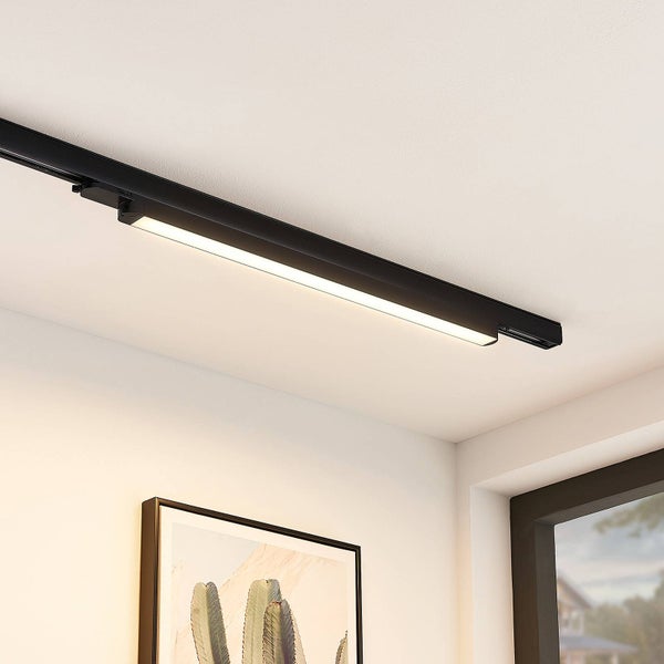 Modernes schwarzes Schienensystem mit leuchtender LED-Linienleuchte an einer weißen Decke in einem hellen Raum mit Wandbild.