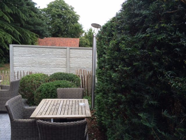 Terrassenszene mit Gartenzaun, Tisch, Stühlen und Außenleuchte