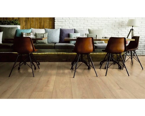 Gastraum mit hellem Holzboden, Sitzgruppe und Stühlen