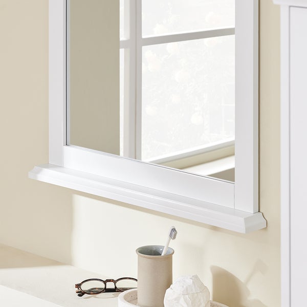 Detailansicht eines weißen Badezimmerspiegels mit Ablagefläche und diversen Badutensilien