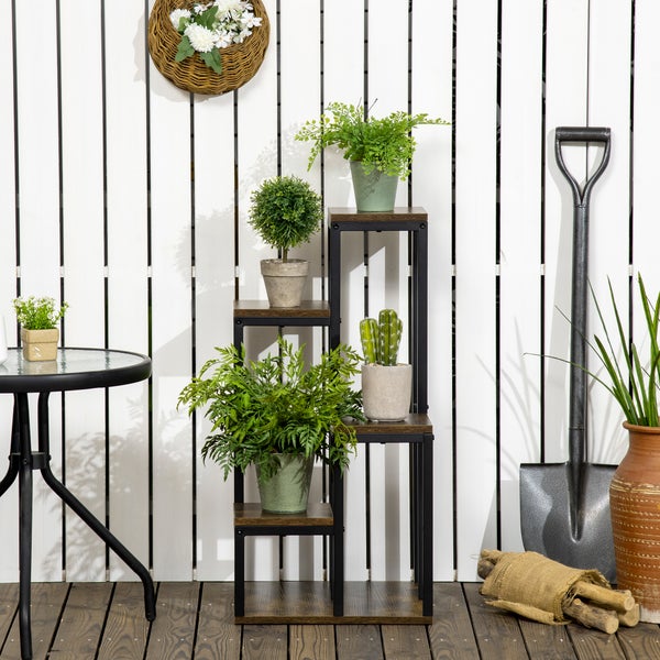 Mehrstöckiges Pflanzenregal aus Metall und Holzoptik auf einer Holzterrasse vor einem Zaun mit verschiedenen Topfpflanzen und Gartenzubehör.