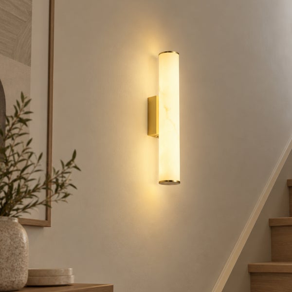 Moderne zylindrische Wandleuchte mit strukturiertem Leuchtschirm an einer Treppenhauswand für eine warme Beleuchtung.
