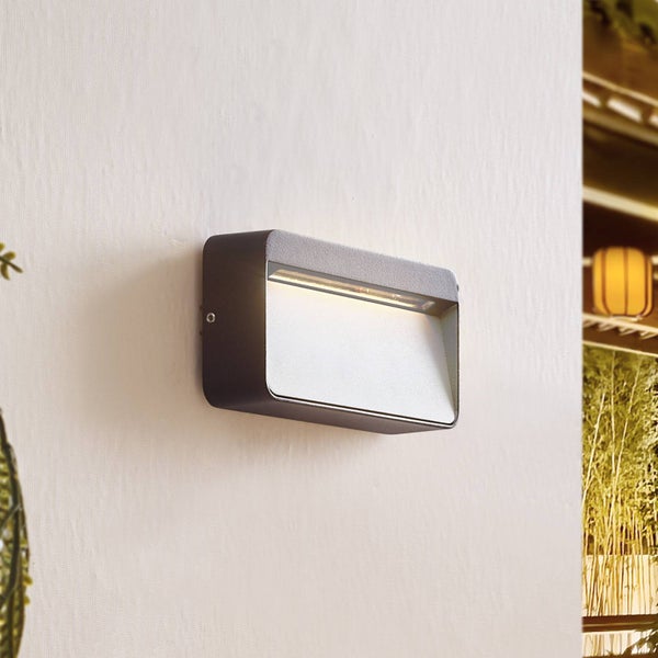 Moderne rechteckige Außenwandleuchte in Anthrazit mit warmem nach unten gerichtetem Licht an einer Wand.