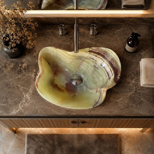 Modernes Badezimmer mit einem unregelmäßig geformten Waschbecken aus Naturstein auf einer dunklen Marmorplatte und einem hölzernen Unterschrank.