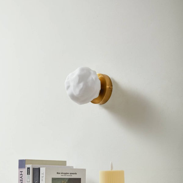 Wandleuchte mit weißem, strukturiertem Schirm und goldfarbenem Metallfuß.