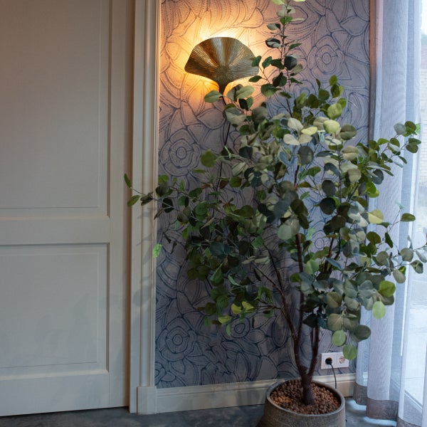 Dekoratives Zimmer mit Wandleuchte, Zimmerpflanze und gemusterter Tapete