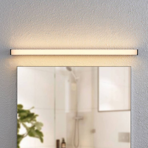 Moderne horizontale LED-Badleuchte in Schwarz über einem Spiegel, warmweißes Licht an einer strukturierten Wand in einem hellen Badezimmer.