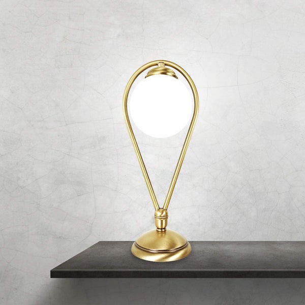 Goldfarbene Tischleuchte mit kugelförmigem Lampenschirm auf einem Regal