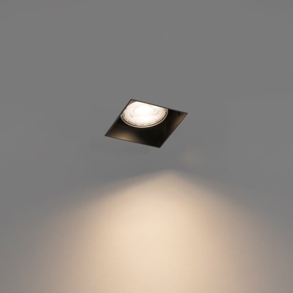 Quadratischer Einbaustrahler in Schwarz für die Decke, eingeschaltet mit warmweißem Lichtkegel nach unten.