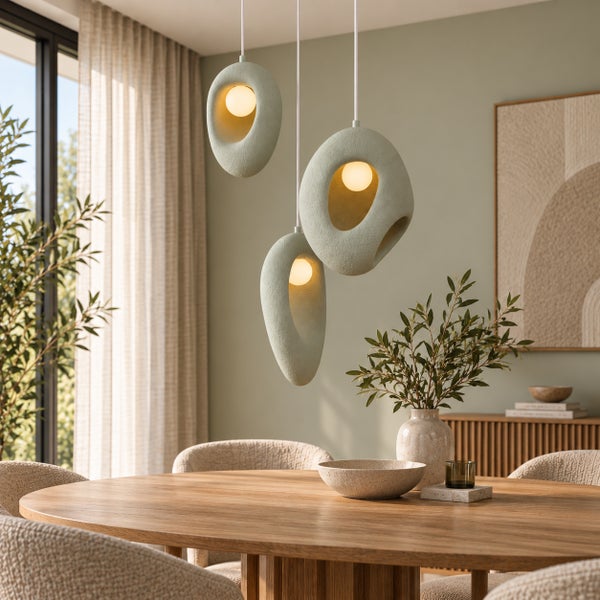 Drei moderne, organisch geformte Pendelleuchten über einem runden Holztisch in einem Esszimmer mit natürlicher Dekoration.