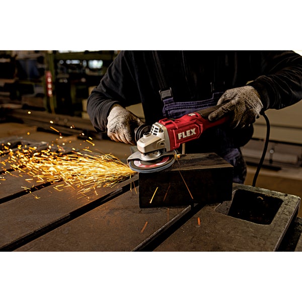 Ein Handwerker mit Schutzhandschuhen benutzt einen Flex Winkelschleifer zum Bearbeiten eines Metallblocks, wobei Funkenflug entsteht.