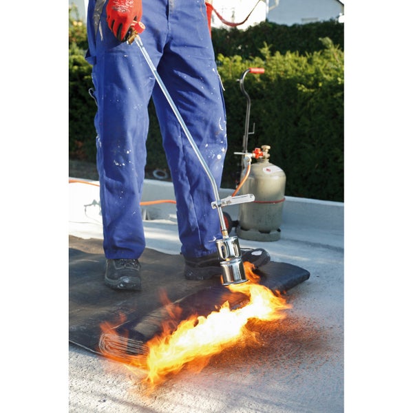 Dachdecker arbeitet mit einem Dachbrenner an einer Bitumenbahn.