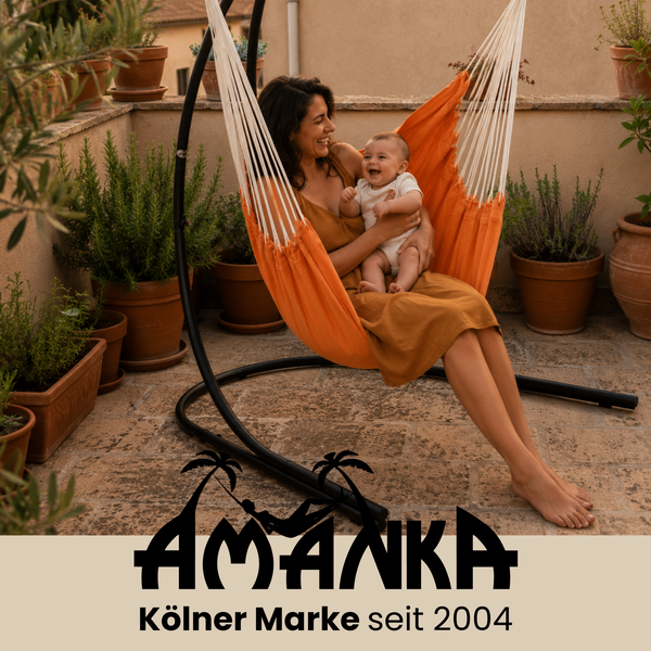 Mutter mit Baby in einem freistehenden Hängesessel auf einer Terrasse. Amanka Logo. Entspannte Atmosphäre mit Pflanzen im Hintergrund.