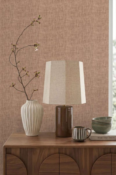 Wohnraum mit strukturierter Vliestapete, einer Tischlampe, einer Vase mit Kirschzweigen und Schalen auf einem hölzernen Sideboard.