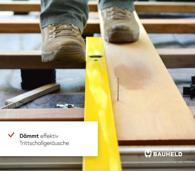 Person steht auf Holzdielen neben Wasserwaage und Schraube