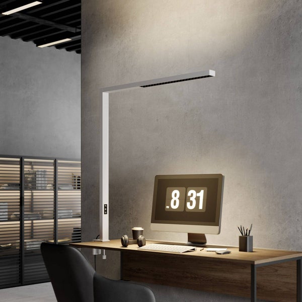 Moderne LED-Schreibtischleuchte in L-Form, befestigt an einem Holzschreibtisch, mit Monitor und Kopfhörern in einem hellen, organisierten Büro.