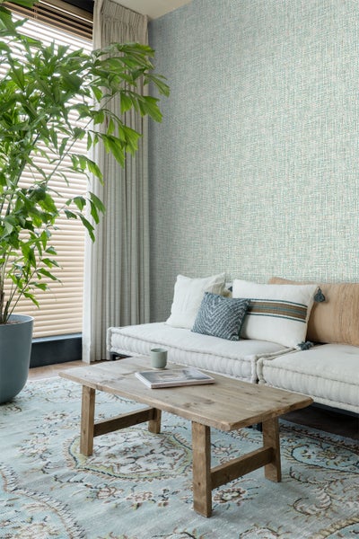 Wohnzimmer mit gemusterter Tapete, Sofa, Holztisch und Zimmerpflanze