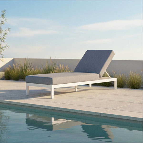 Moderne Gartenliege mit weißem Metallrahmen und grauen Polstern auf einer hellen Steinterrasse am Pool in heller, aufgeräumter Atmosphäre.