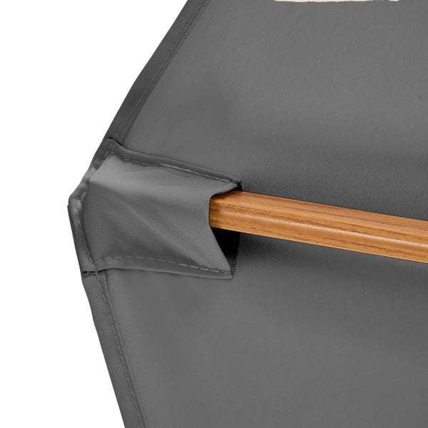 Detail eines grauen Sonnenschirms mit einer Holzstrebe in einer Stofftasche.