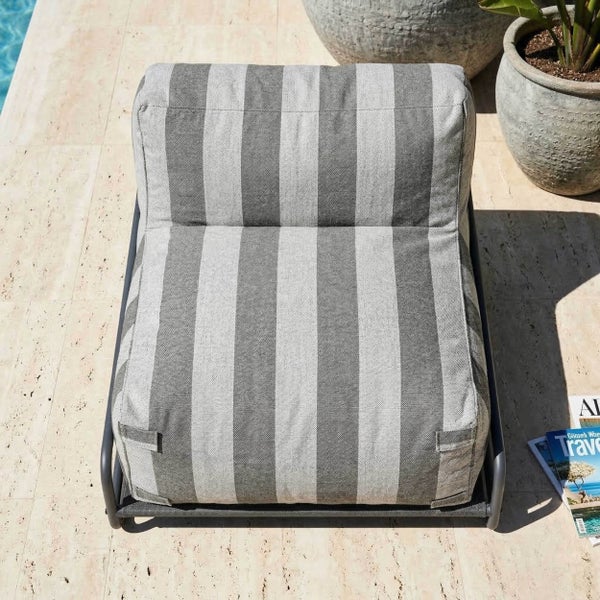 Gestreifter Outdoor-Lounge-Sessel auf einem grauen Metallgestell auf einer Steinterrasse am Pool.