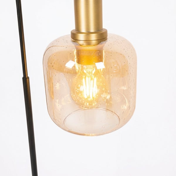 Nahaufnahme einer Leuchte mit messingfarbener Fassung, bernsteinfarbenem Blasenglas-Schirm und leuchtendem LED-Filament-Leuchtmittel.