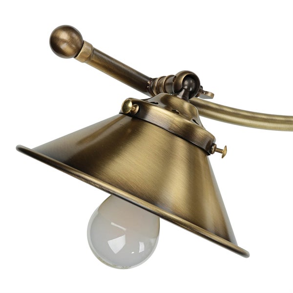 Detailansicht einer Messinglampe mit konischem Schirm und Glühbirne