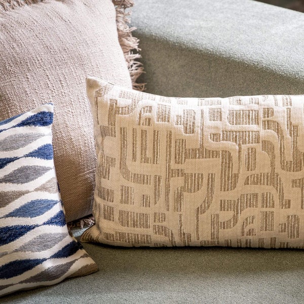 Nahaufnahme von drei dekorativen Kissen mit unterschiedlichen Mustern auf einem Sofa