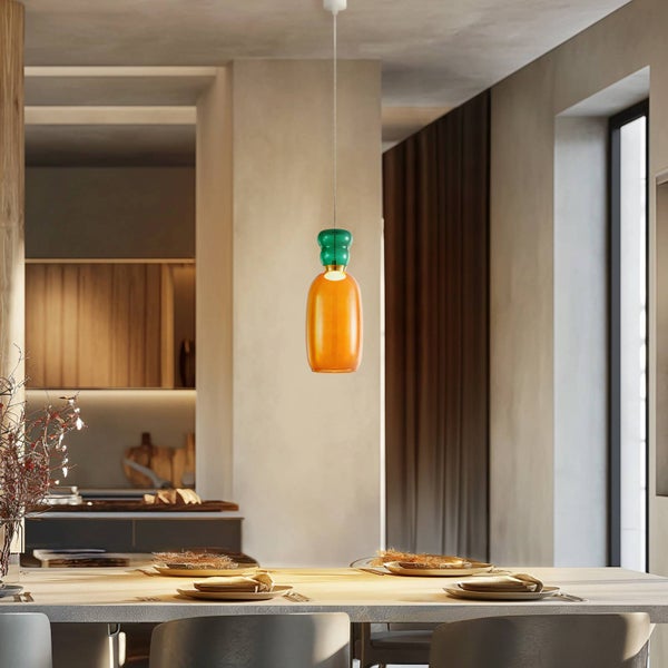 Pendelleuchte aus Glas über einem Esstisch in einem hellen, offen gestalteten Wohnbereich mit Blick auf die moderne Küche.