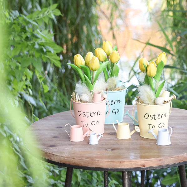 Dekorative Blumentöpfe mit Tulpen und Ostereiern auf einem Gartentisch