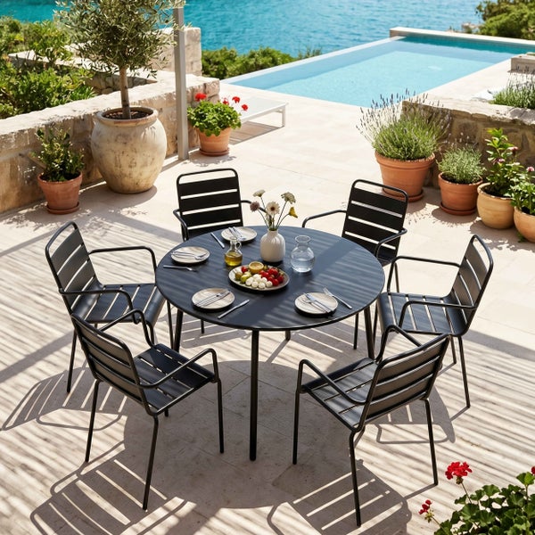 Schwarzes Gartenmöbel-Set aus Metall mit rundem Tisch und sechs Armlehnenstühlen auf einer sonnigen Terrasse mit Pool und Meerblick.