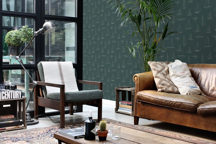 Vliestapete mit Segelboot-Muster in einem rustikalen Wohnzimmer mit Ledersofa, Holzsessel und Vintage-Möbeln.