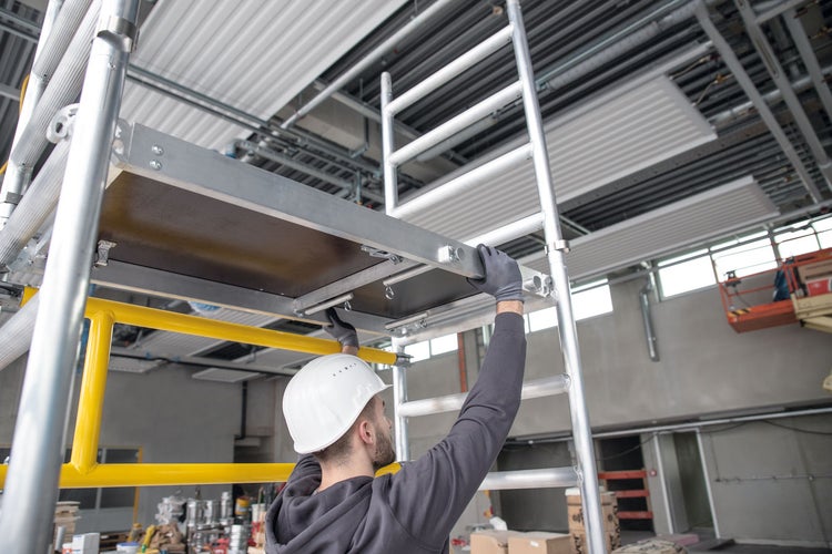 Ein Bauarbeiter montiert ein Gerüst in einem Gebäude.