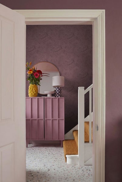 Einladender Flur mit Kommode, Spiegel, Lampe und Blumenvase, Tapete mit floralem Muster und Treppe