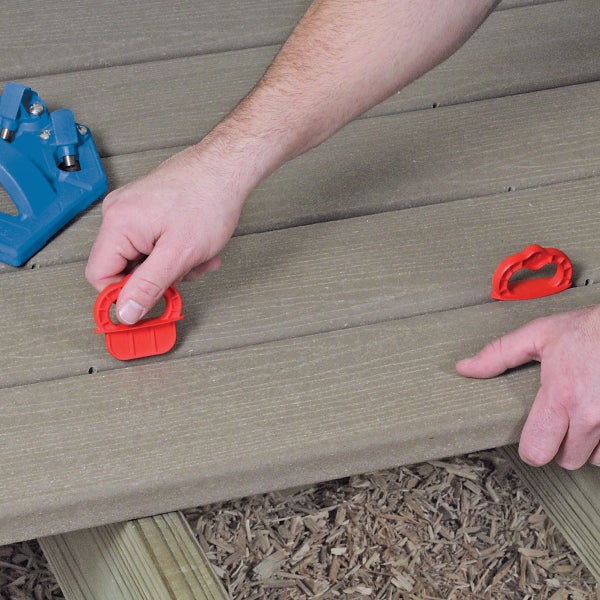 Person verwendet eine blaue Terrassenbau-Bohrhilfe und einen Schlagschrauber zur Befestigung von Holz-Terrassendielen.