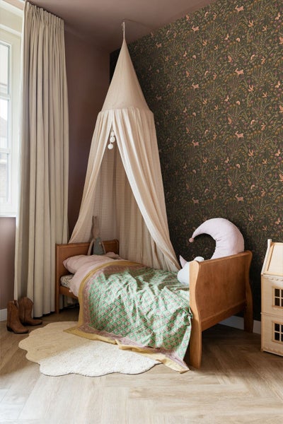Kinderzimmer mit Holzbett, Baldachin, gemusterter Waldtapete mit Blumen und hellem Fischgrät-Parkett.