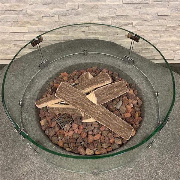 Runde Gas-Feuerstelle in Steinoptik mit Lavasteinen, Keramik-Holzscheiten und einem runden Windschutz aus Glas.