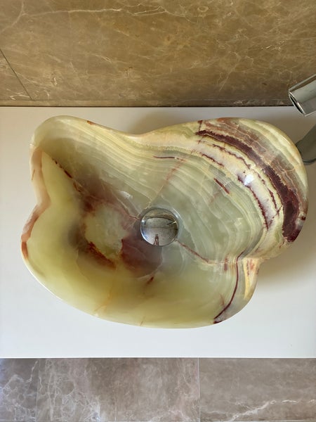 Organisch geformtes Aufsatzwaschbecken aus Naturstein Onyx mit markanter Maserung.