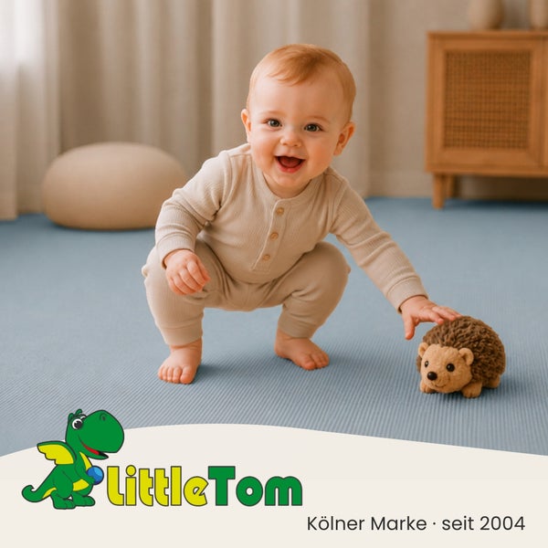 Ein lächelndes Baby spielt auf einer blauen Bodenmatte mit einem Igel Stofftier. Little Tom Logo.